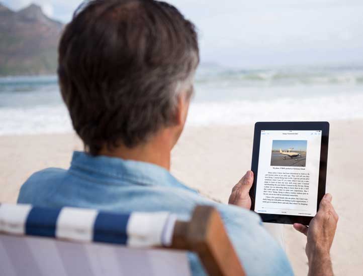 Ebook being read on a Kindle ereader at a sandy beach.